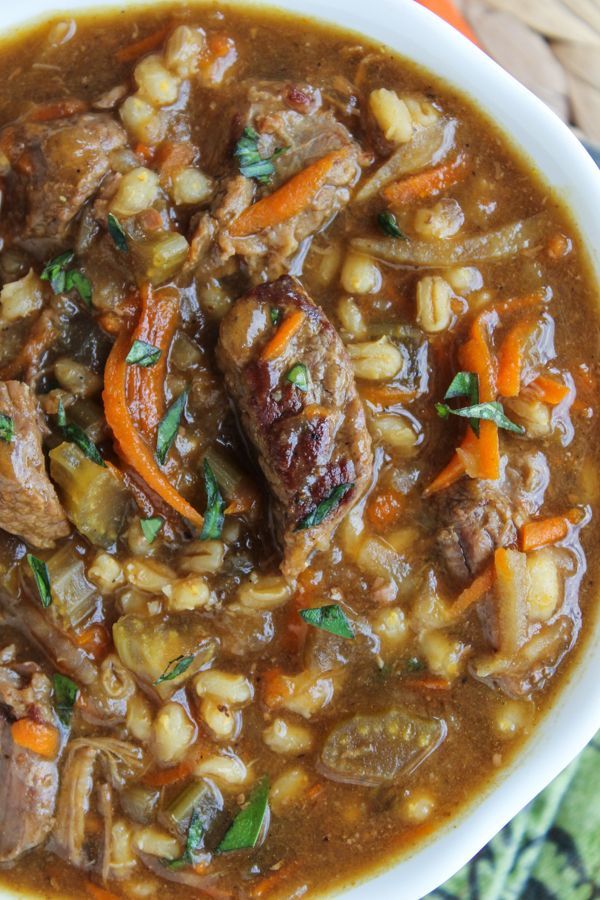 a white bowl filled with stew and carrots on top of a green table cloth