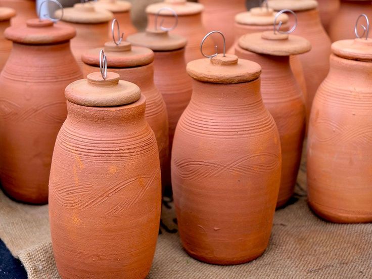 many clay pots are lined up on a table with pins in them, and the tops have been turned upside down