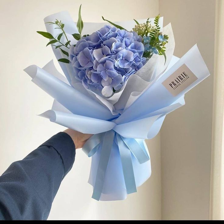 a person holding a bouquet of blue flowers