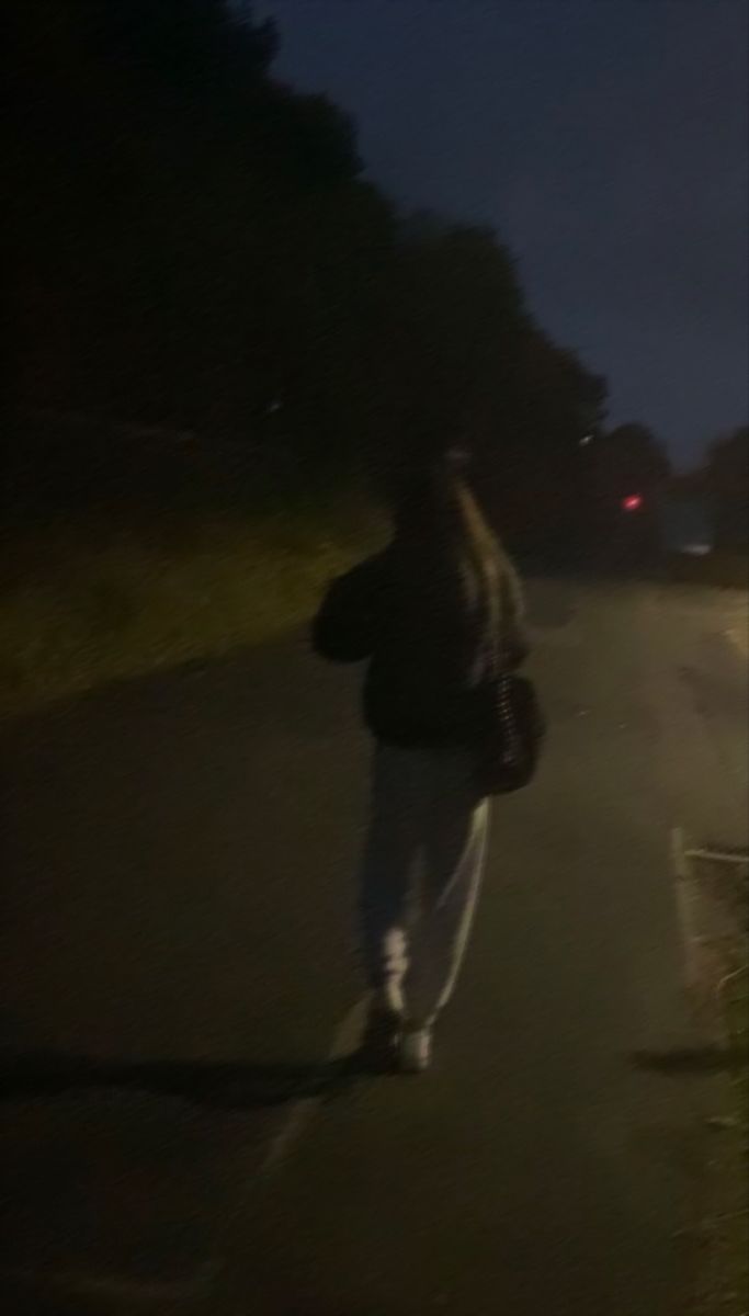 a person is walking down the street at night with their back turned to the camera