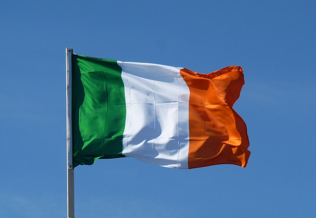 the irish flag is flying high in the sky