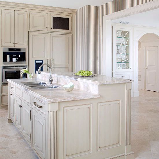 a large kitchen with white cabinets and marble counter tops