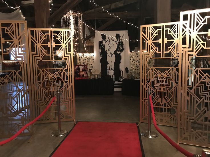 a red carpet is in between two gold gates with an art work on the wall