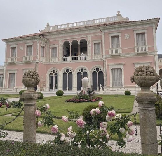 a large pink house with lots of flowers in the front yard