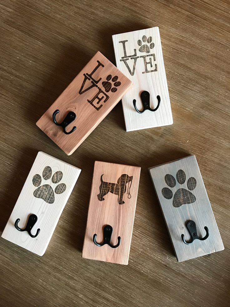 four wooden door hangers with different designs and animals on them, one has a dog's paw in the middle