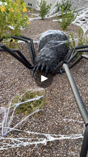 a large spider statue sitting on top of a gravel ground