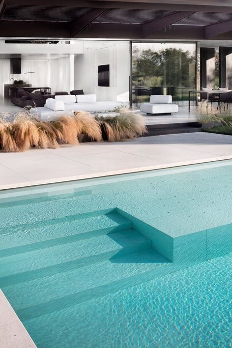 an empty swimming pool in front of a modern house