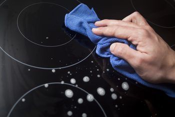 a person cleaning an oven with a blue cloth