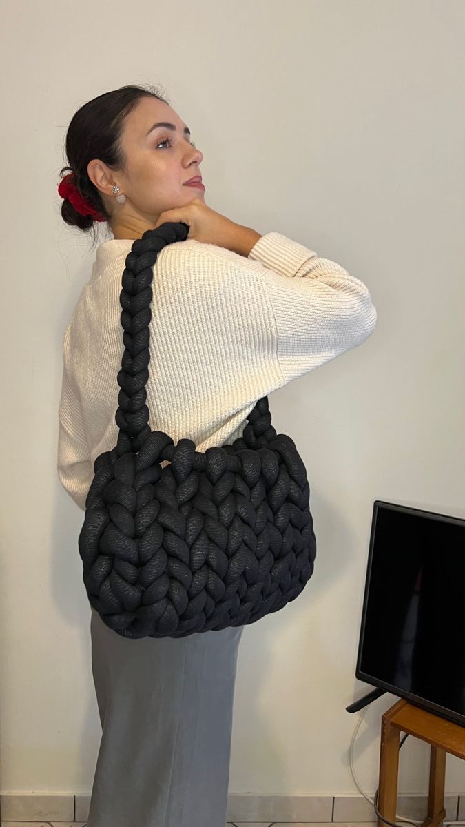 a woman is holding a black handbag in front of her face