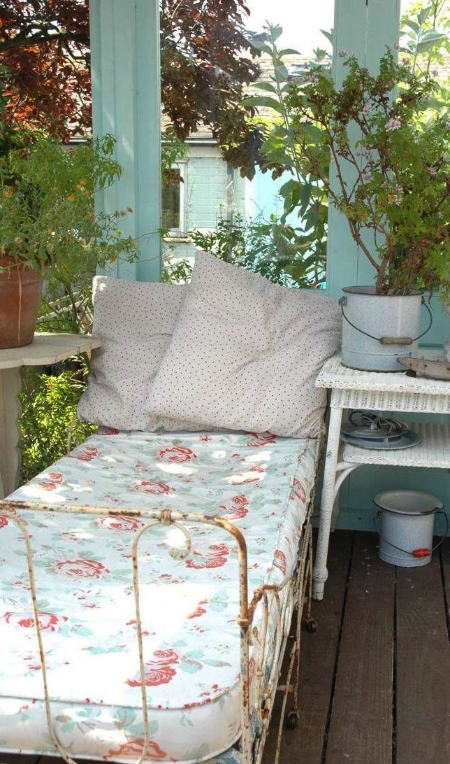 a bed sitting on top of a wooden floor next to potted plants