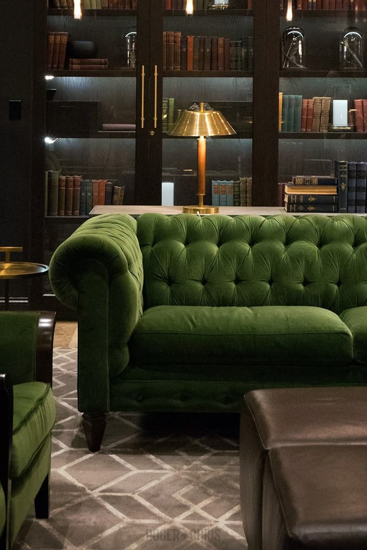 a living room filled with green couches next to a book shelf full of books