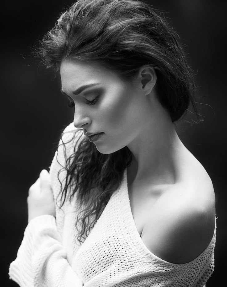 black and white photograph of a woman with her hair blowing in the wind, wearing a sweater