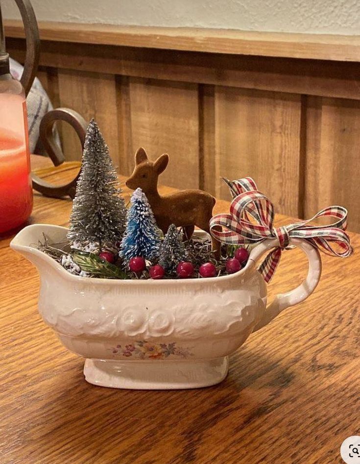 a ceramic bowl filled with christmas decorations on top of a wooden table