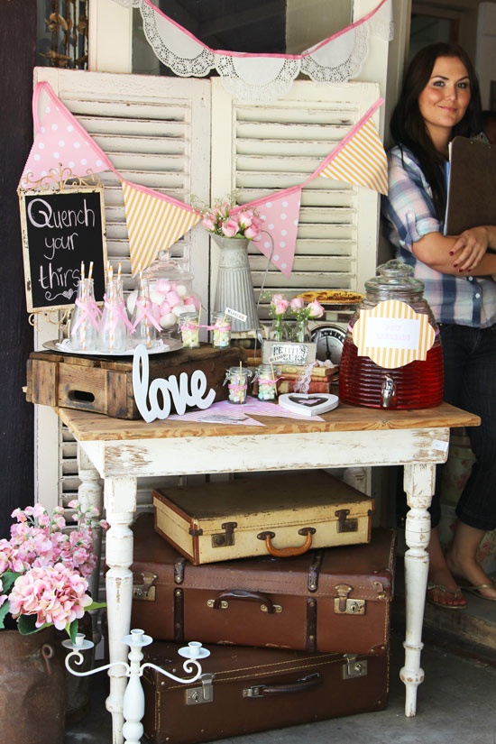 a woman standing in front of a table filled with suitcases and other items on it