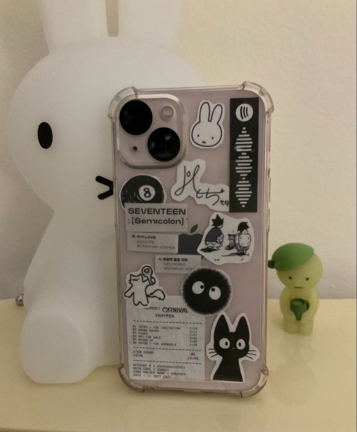 an iphone case with stickers on it next to a stuffed animal and a toy