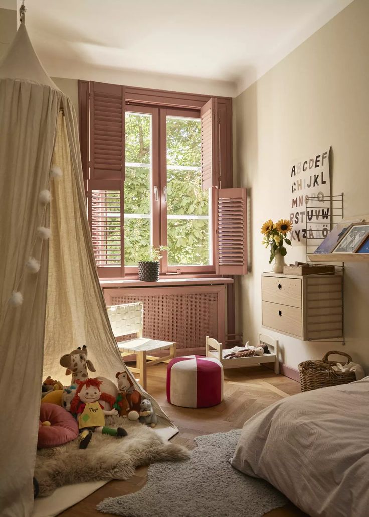 a child's bedroom with a canopy bed and stuffed animals on the floor next to it