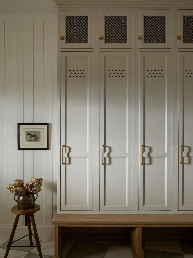 a room with white cupboards and a wooden bench in it's center area