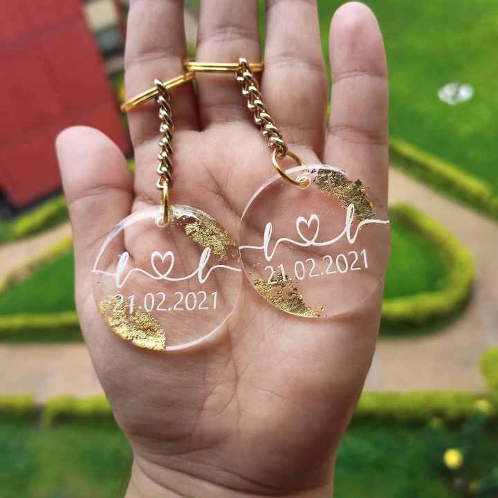 someone is holding two clear glass keychains in their hand with the date and year on them