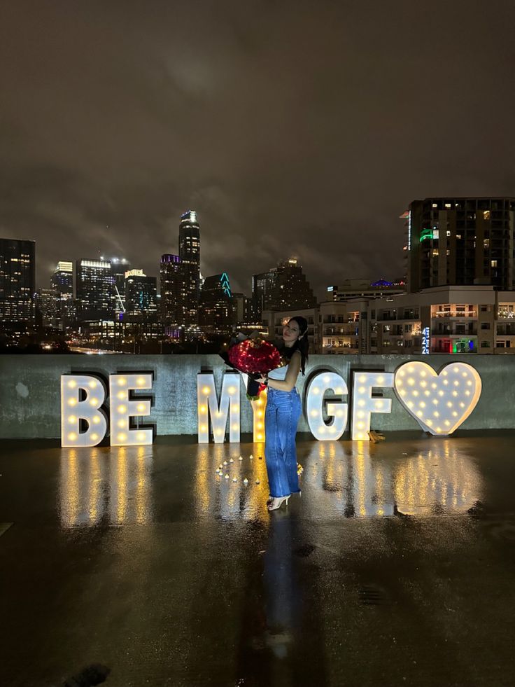 two people standing next to each other in front of a sign that says be my girlfriend