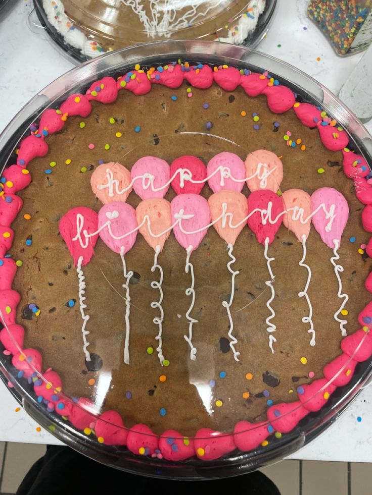 a birthday cake decorated with pink and white balloons