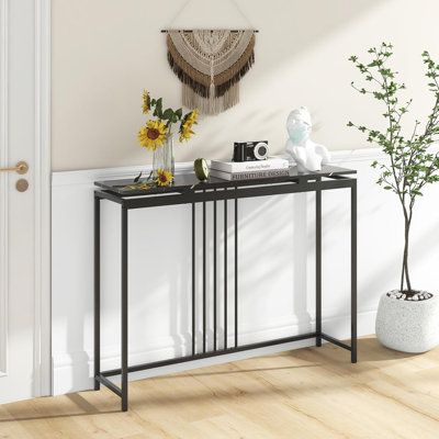 a black metal console table with two vases and flowers on the shelf next to it