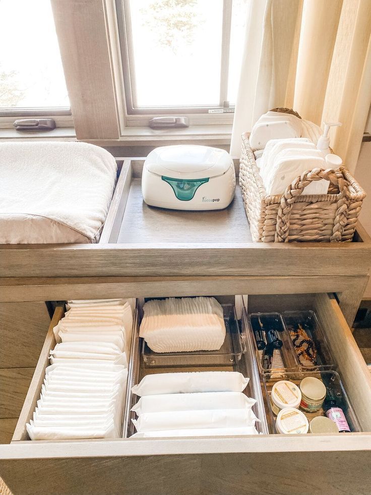 an open drawer in a bed room next to a window with towels and other items