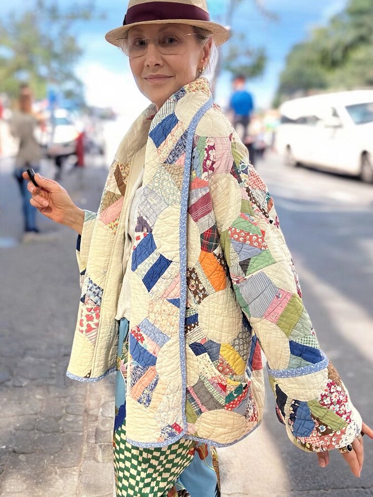 a woman in a hat and jacket walking down the street