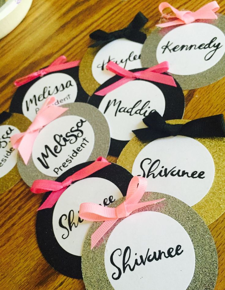 six name tags with bows on them sitting on a table