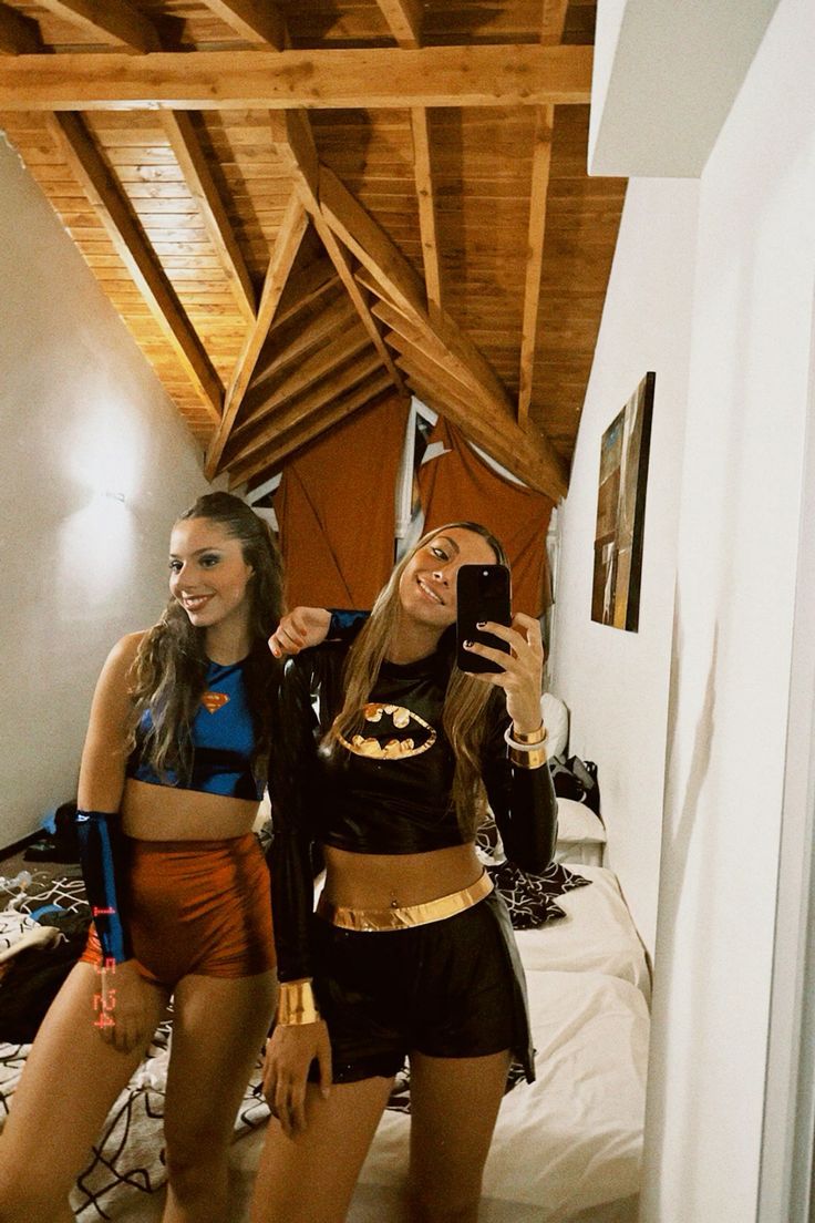 two young women dressed in costumes taking a selfie with their cell phone while standing next to each other