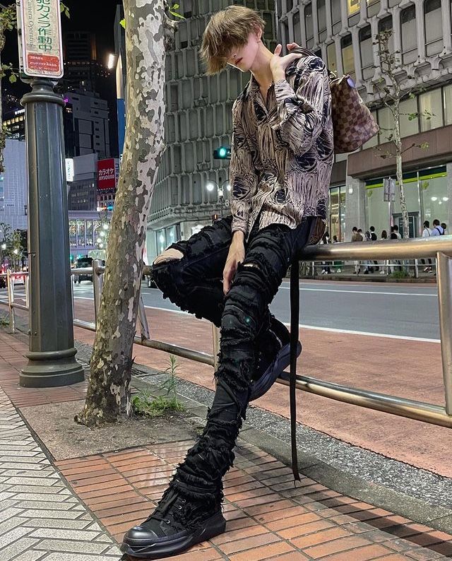 a young man sitting on a bench next to a tree