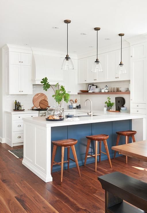 a kitchen with white cabinets and wooden stools next to an island in the middle