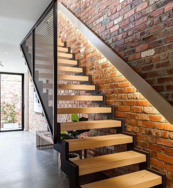 there is a stair case with wooden steps next to brick wall and planter in the corner