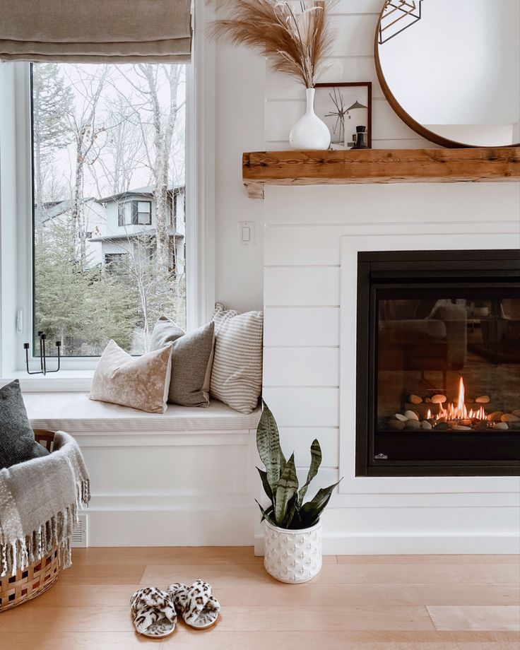 a living room with a fire place in the fireplace and some pillows on the floor