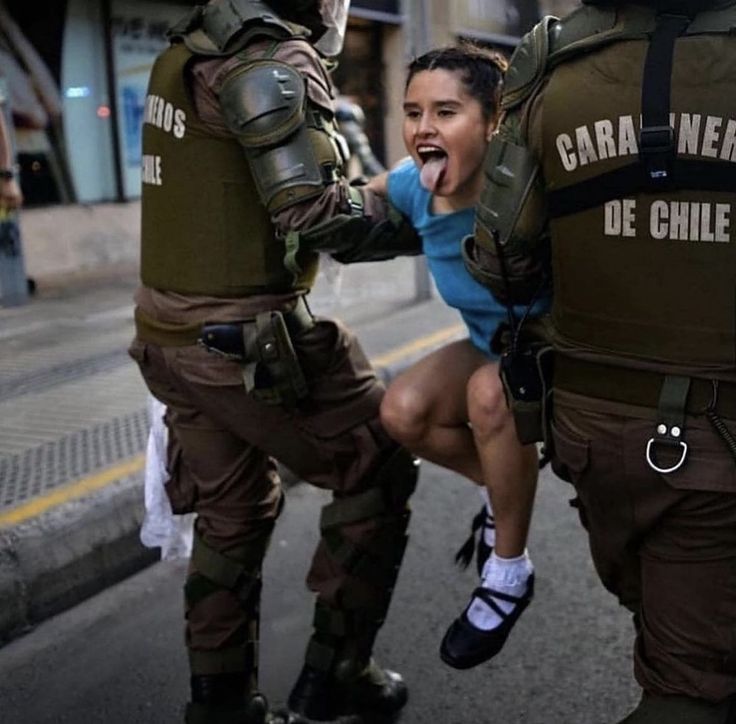 a woman is being restrained by police officers on the street while another person holds her back