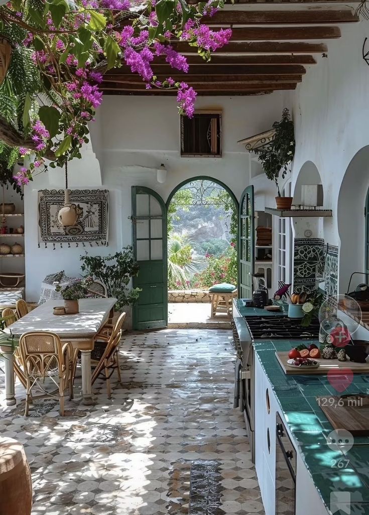 the kitchen is decorated in white and has green doors leading to an outdoor patio area