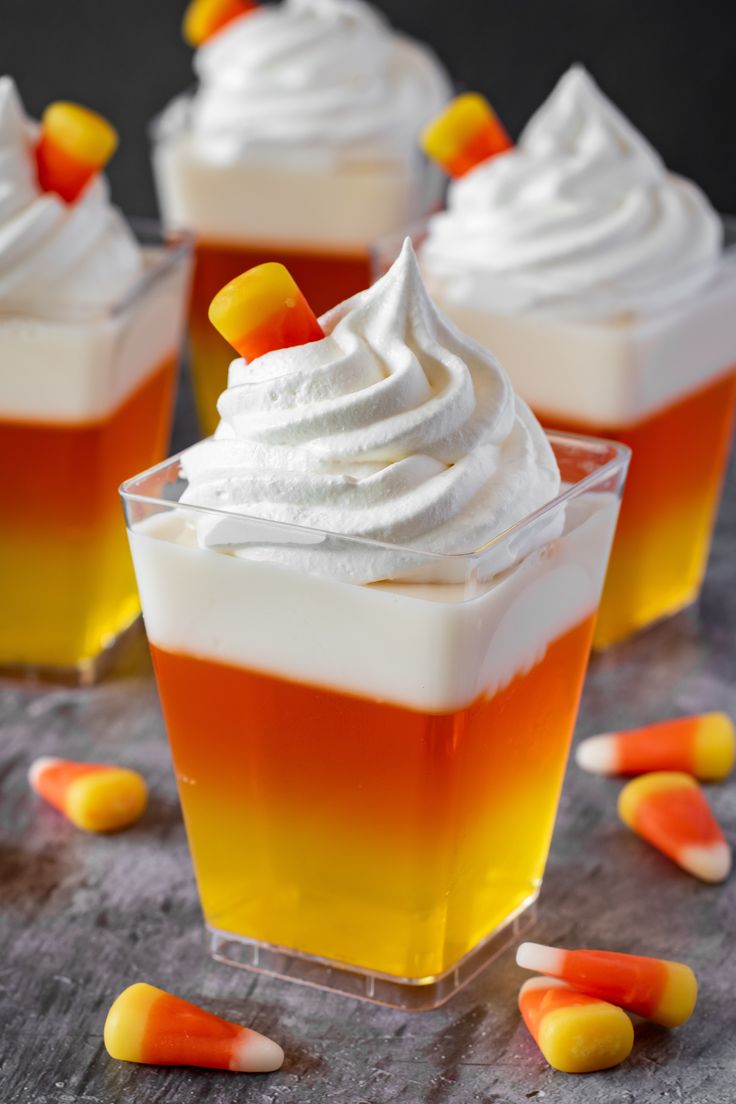 three dessert cups with candy corn and whipped cream