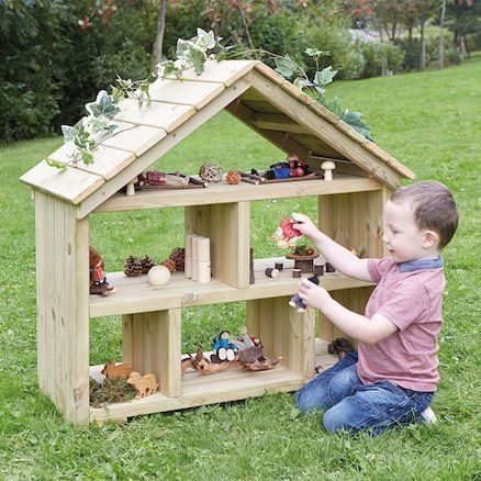 a little boy playing with a wooden toy house