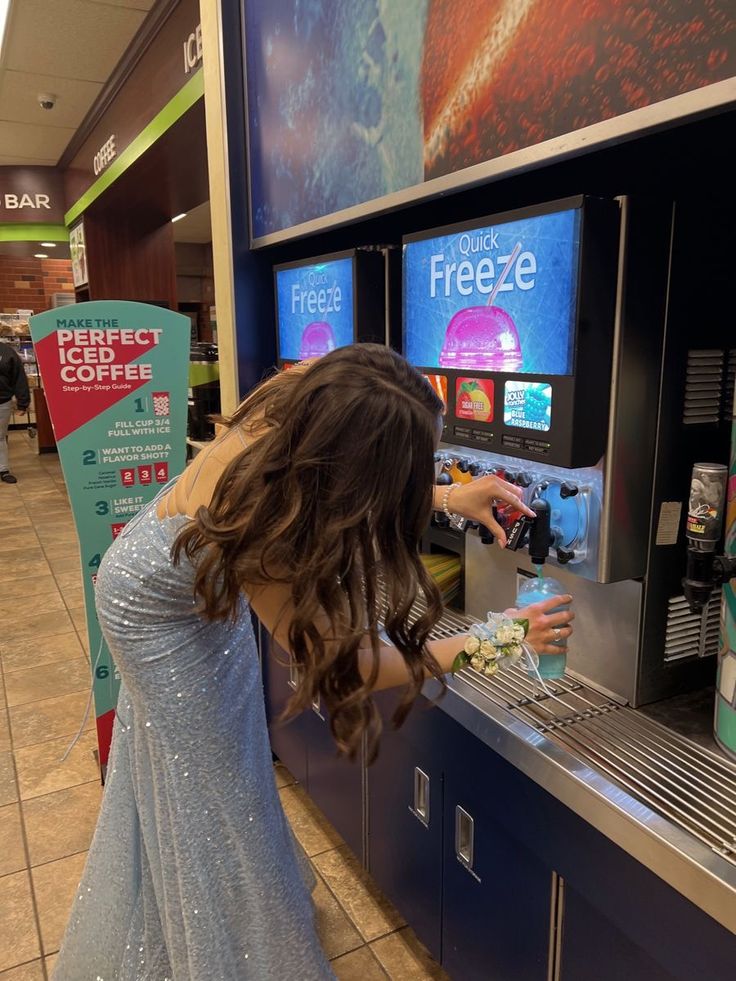 a woman in a blue dress is at a vending machine with her hand on the counter