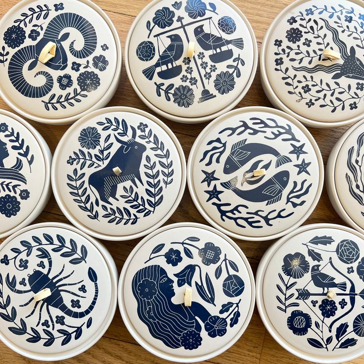 twelve blue and white plates sitting on top of a wooden table next to each other