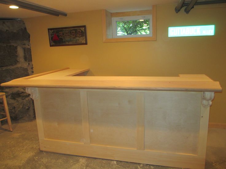 an unfinished kitchen counter in the middle of a room with two stools and a stone fireplace