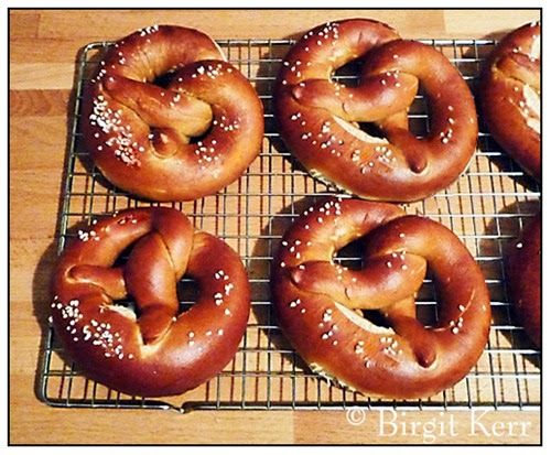 six pretzels on a cooling rack with sesame seeds