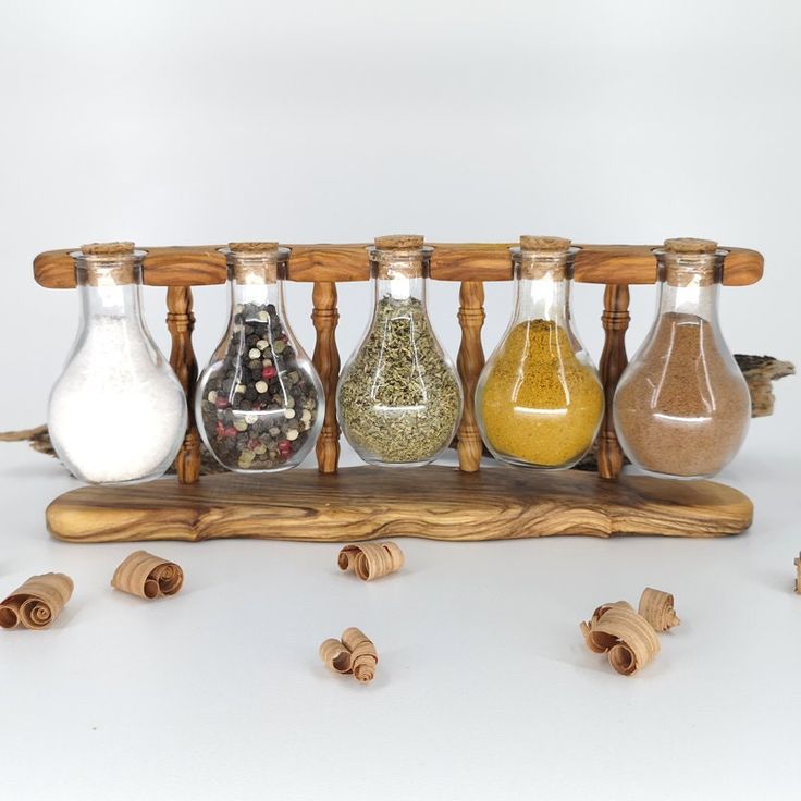 an assortment of spices in glass bottles lined up on a wooden rack