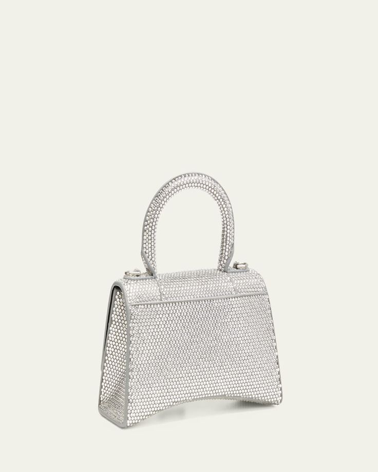 Balenciaga "Hourglass" top handle bag in strassed calf leather and suede with silvertone hardware    Features hanging B logo on front     Rolled top handle     Detachable, adjustable crossbody strap, 21.6"L    Flap top with magnetic closure     One interior compartment     Approx. 5.1"H x 7.4"W x 3.1"D    Spot clean    Made in Italy Luxury Silver Shoulder Bag With Detachable Handle, Luxury Handheld Satchel With Silver-tone Hardware, Luxury Silver Bag With Double Handle, Silver Shoulder Bag With Round Handle For Evening, Luxury Silver Double Handle Bag, High-end Silver Bag With Palladium Hardware, Chic Silver Bag With Round Handle, Designer Silver Bag With Detachable Handle, Chic Silver Shoulder Bag With Round Handle