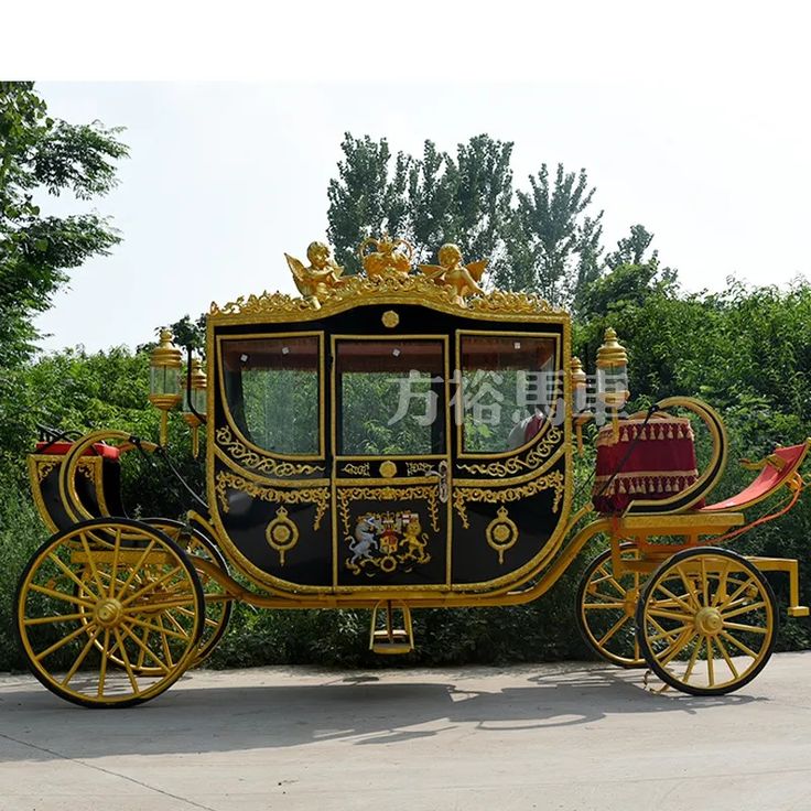 a gold and black horse drawn carriage parked on the side of a road with trees in the background