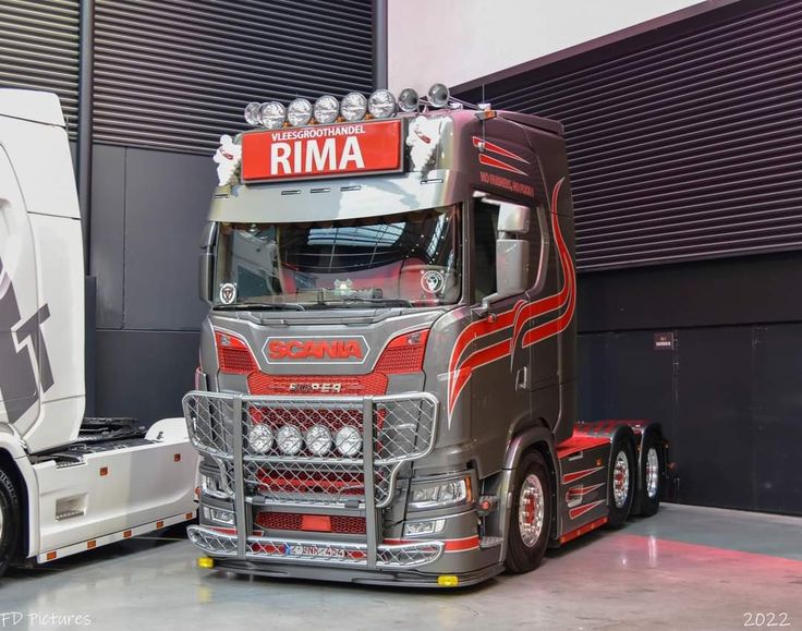 a large semi truck parked in front of a garage door with the word rima on it's side