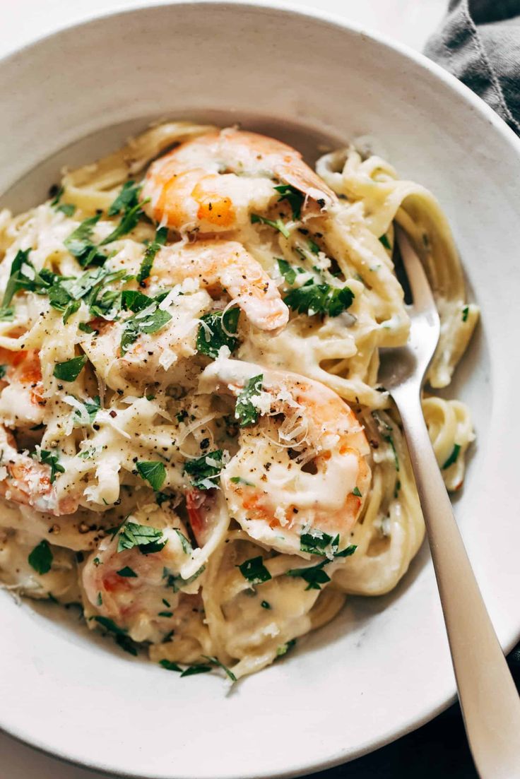 a white bowl filled with pasta and shrimp