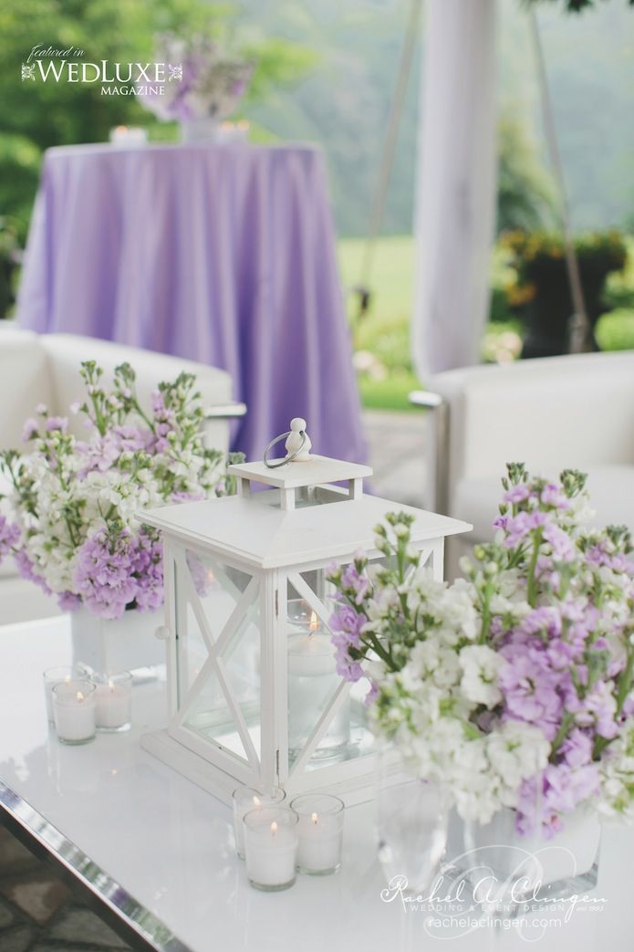 white and purple flowers in vases sitting on a table next to a candle holder