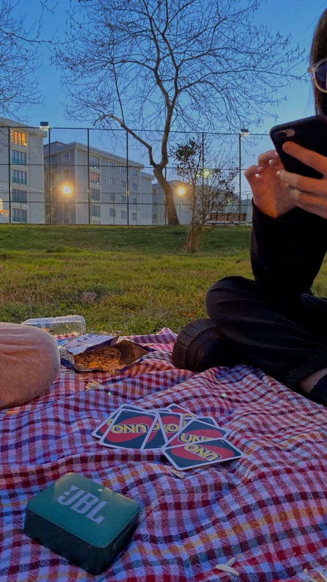 a person sitting on a blanket looking at a cell phone