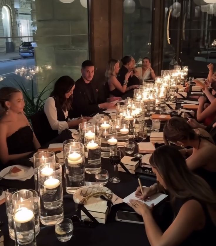 a group of people sitting around a table with candles on it