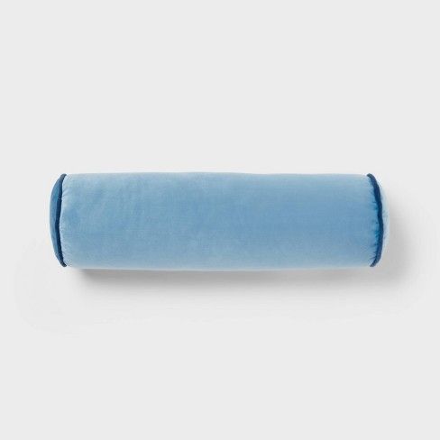 a rolled up blue pillow sitting on top of a white wall